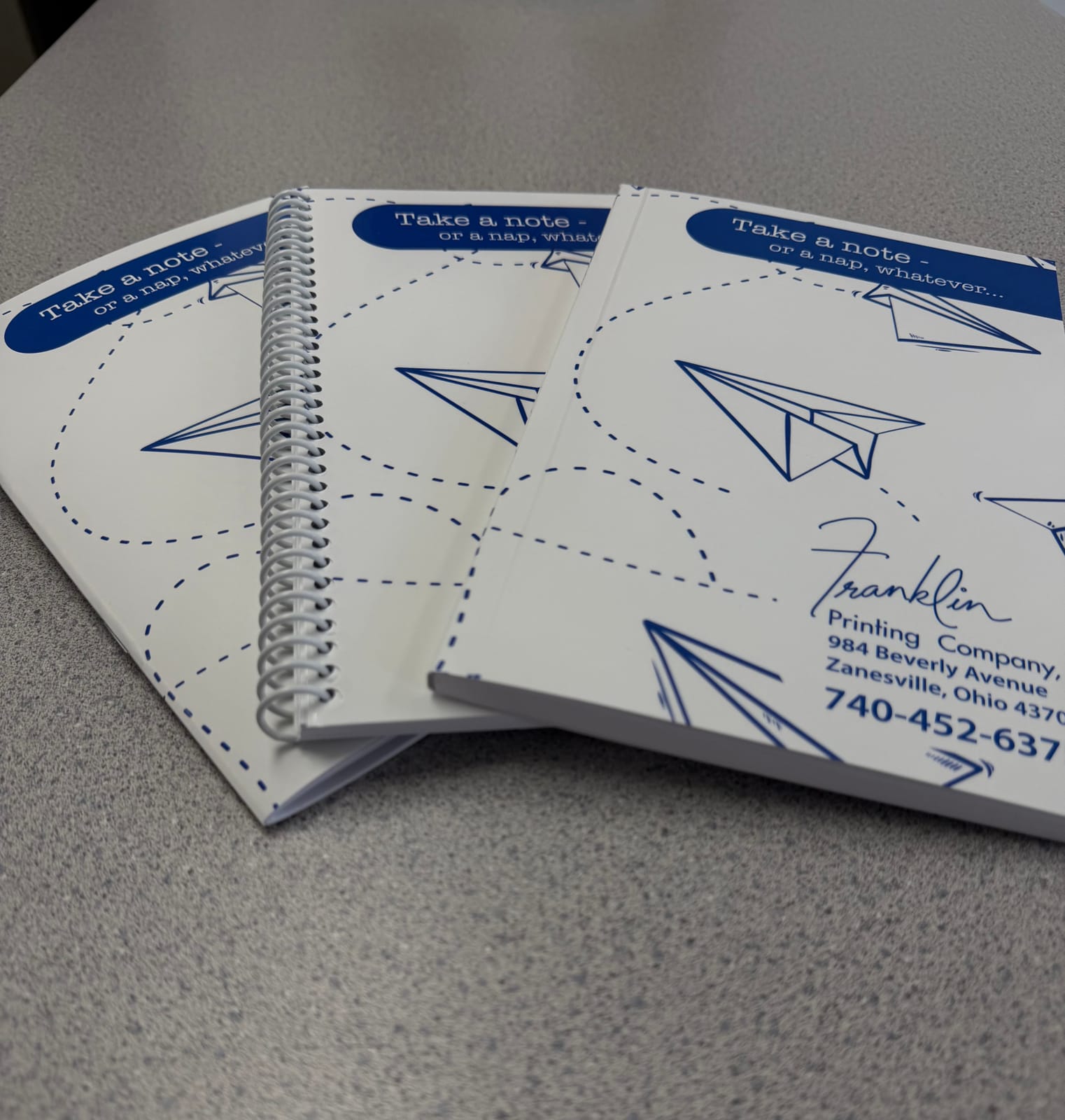 Three custom notebooks printed and bound at Franklin, fanned out on a worktop
