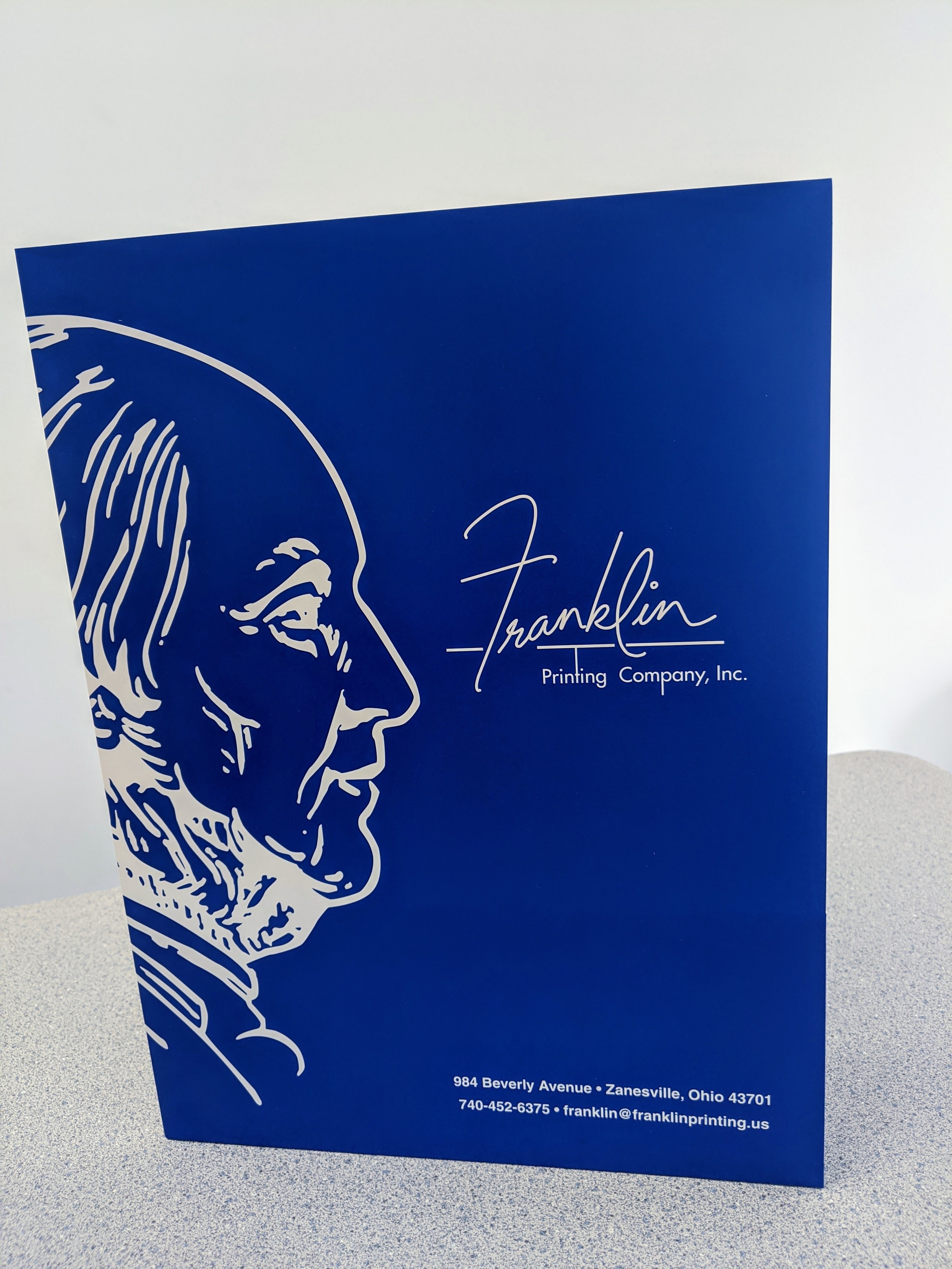 Royal-blue presentation folder with the Ben Franklin profile mark